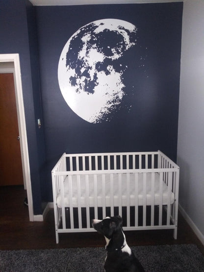 White moon decal on a black wall in a nursery. 