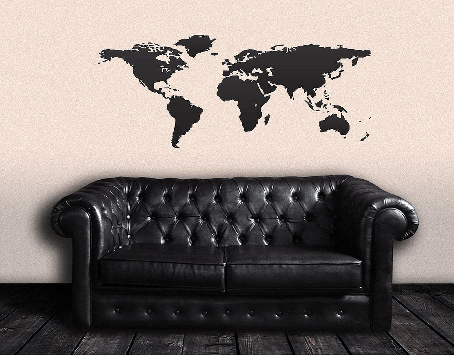 Black world map decal on a white wall above a black couch.