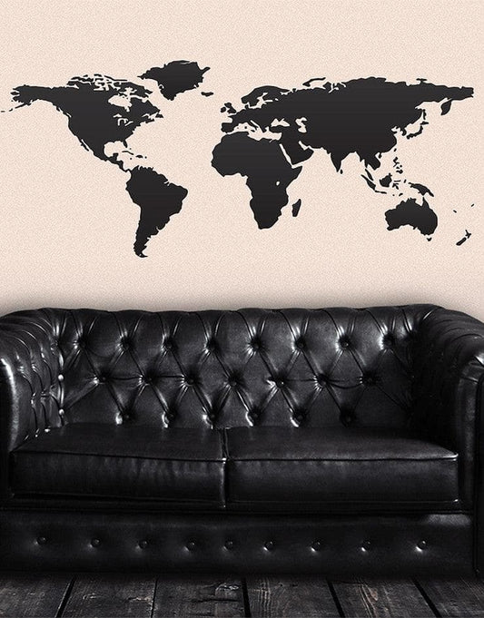 Black world map decal on a white wall above a black couch.