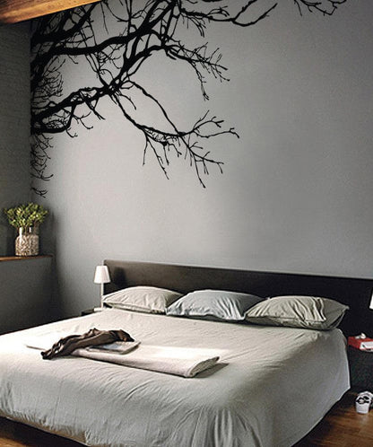 A bedroom with a black tree decal on the wall.