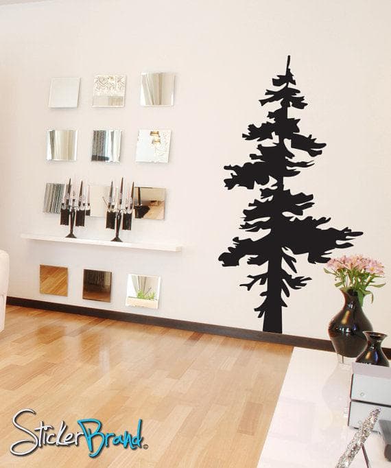 A black pine tree decal on a white wall near framed photographs.