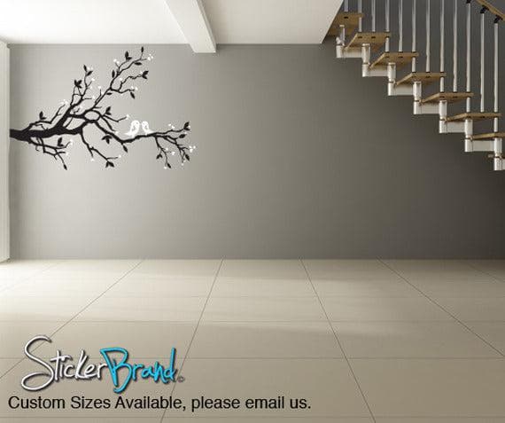 A black decal of a tree branch with two birds on a gray wall.