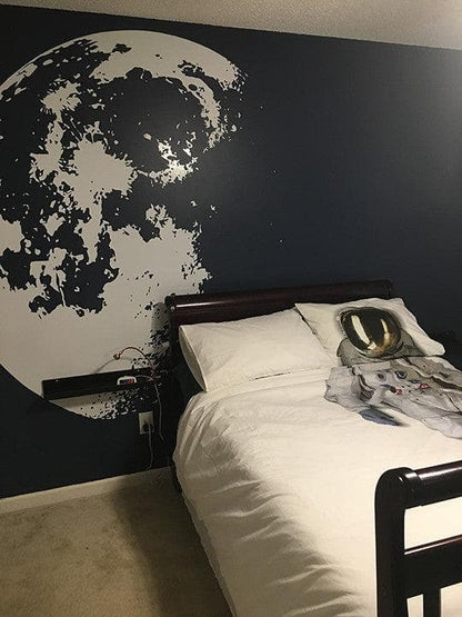 White moon decal on a black wall in a bedroom. 