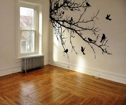 Black decal of 8 birds on tree branches on a white wall.