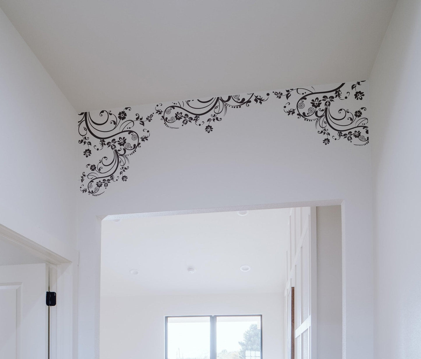 Black floral swirling decals on a white wall. 