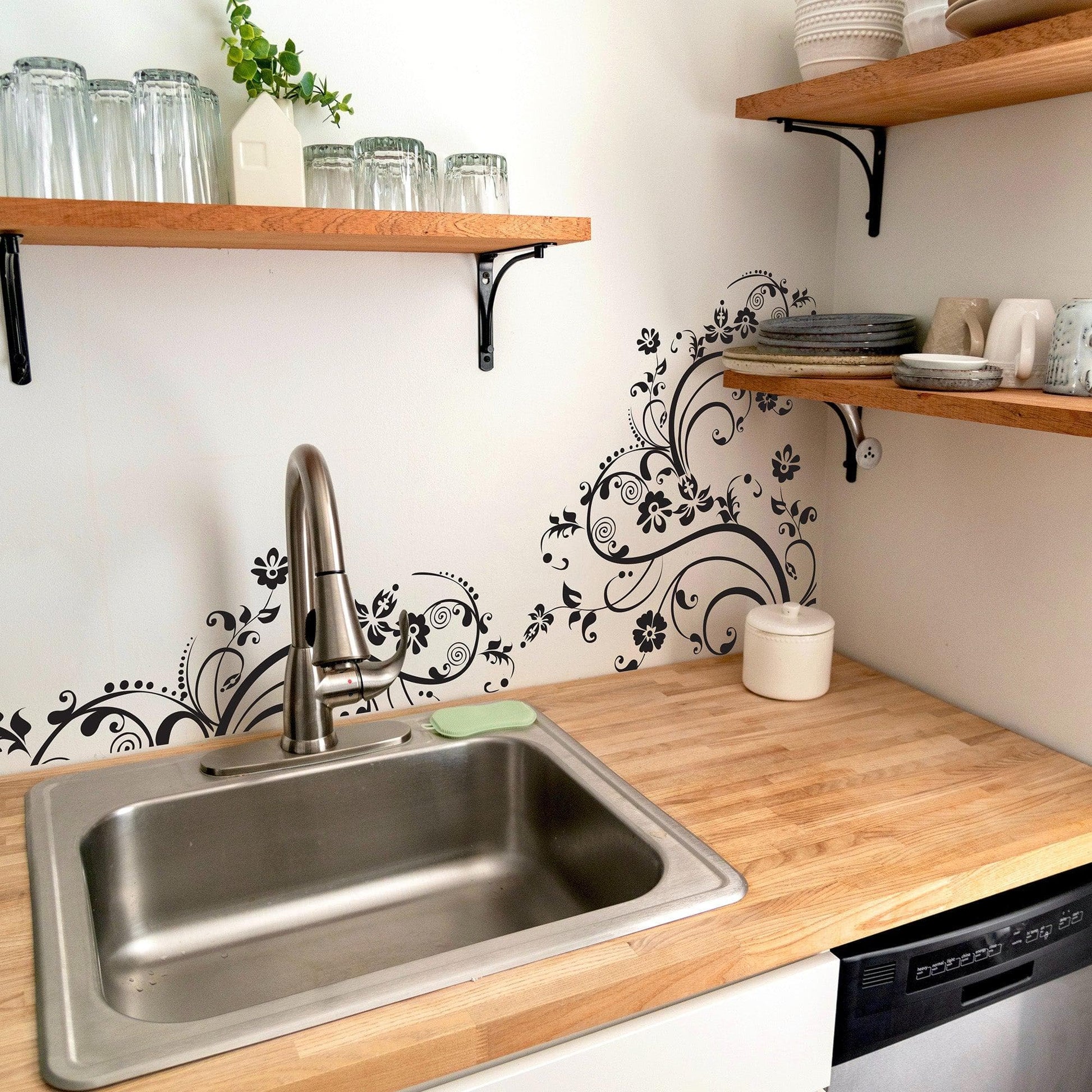 Black swirling floral decals on a white wall in a kitchen.