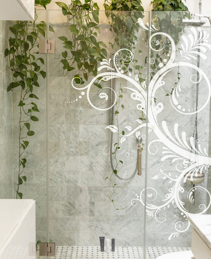 A white floral swirl decal on a bathroom glass door. 