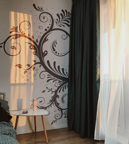 A black floral swirl decal on a white wall in a bedroom.
