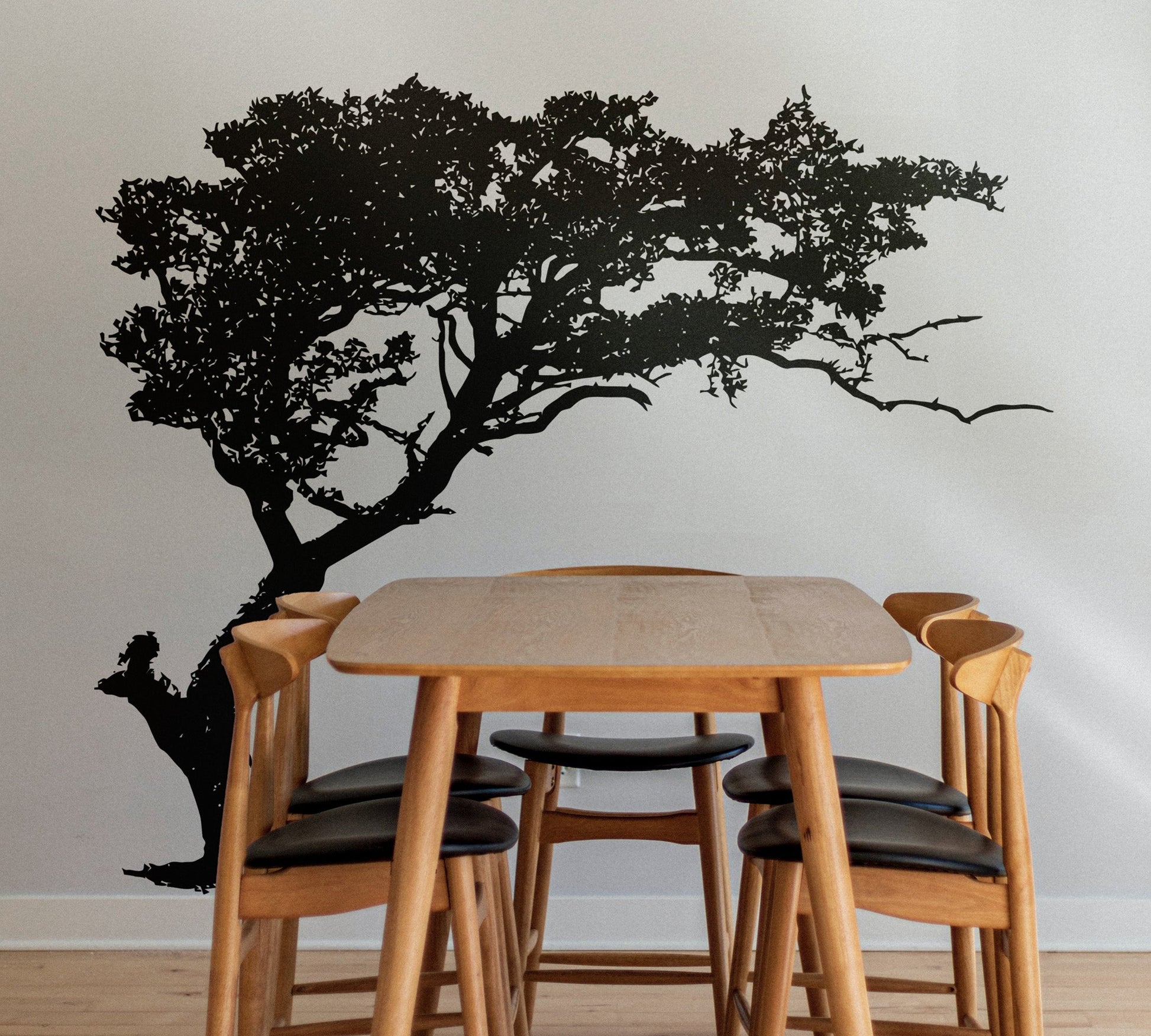 Black tree decal on a white wall in a dining room.