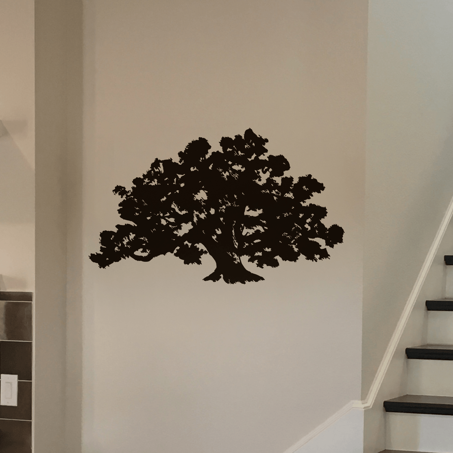 A black tree decal on a white wall near a staircase.