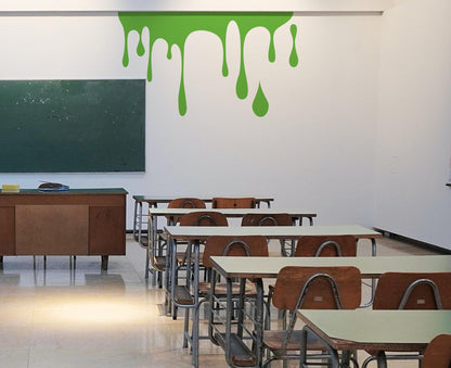 A green decal of slime on a white wall in a classroom.