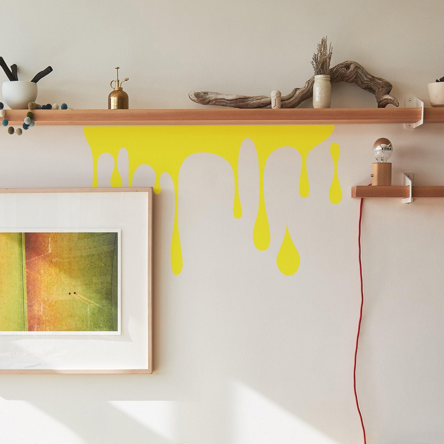 A yellow decal of slime on a white wall near a wooden shelf and frame.