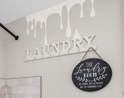 A white decal of slime on a white wall near a wooden laundry sign.