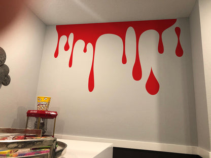 A red decal of slime on a white wall near a popcorn machine.