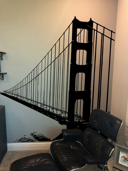 A black decal of the Golden Gate Bridge on a white wall near a black chair.