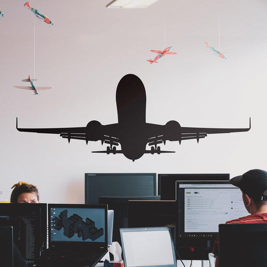 A black decal of an airplane on a white wall in an office. 