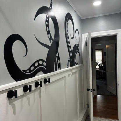 A black octopus tentacle decal on a gray wall in a bedroom.