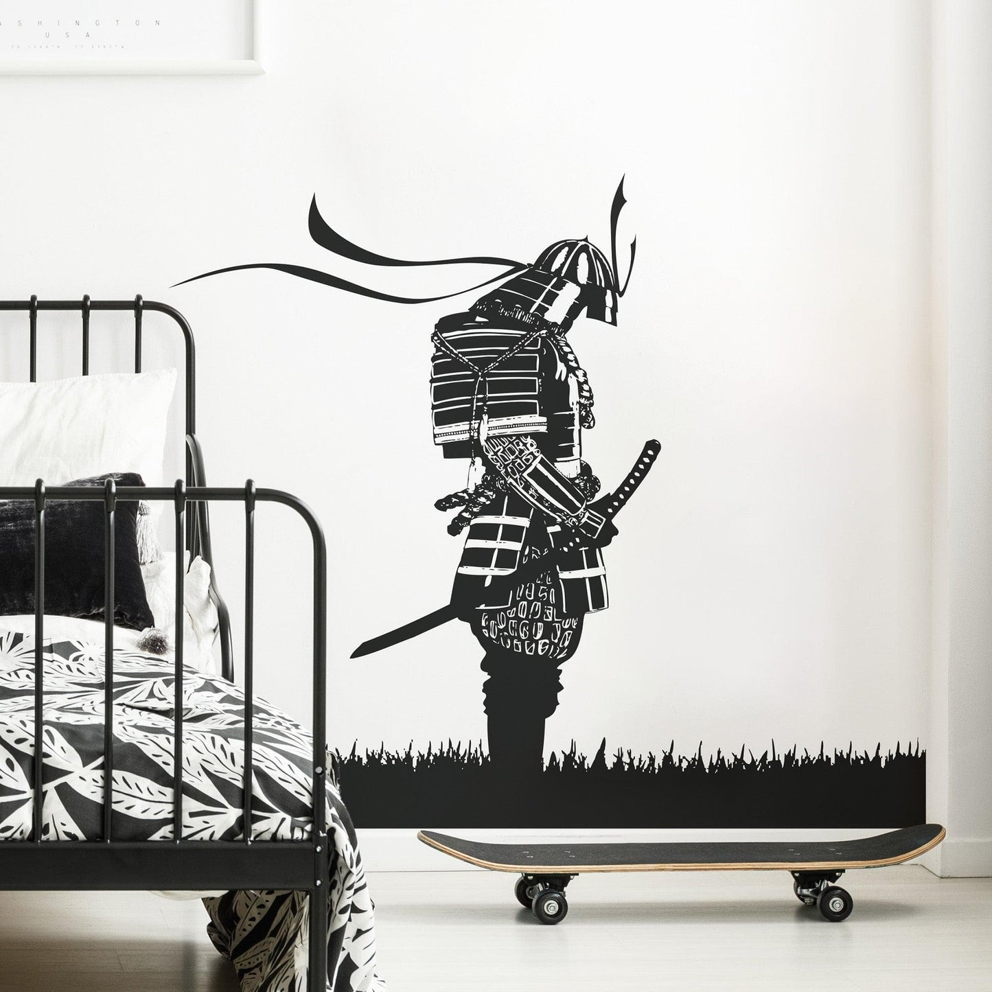 A black decal of a samurai on a white wall in a bedroom near a skateboard. 