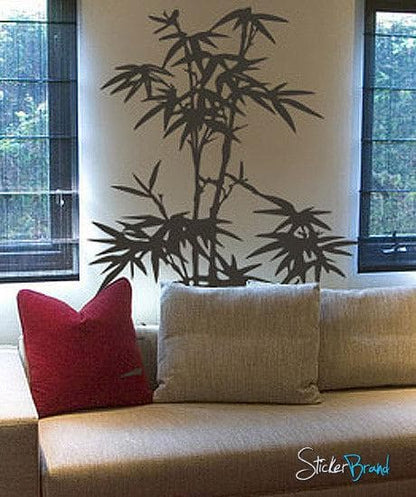 A gray bamboo tree decal on a white wall near a couch and two windows.