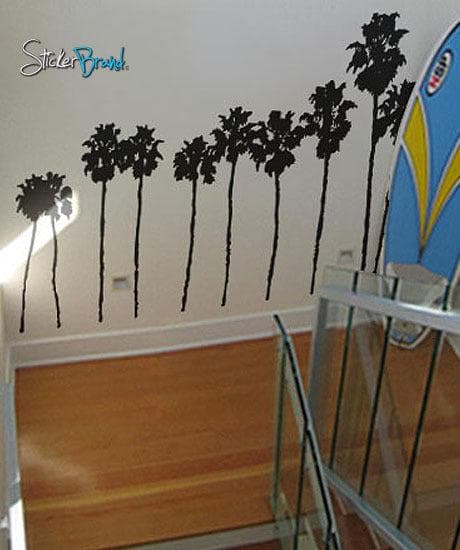 A black decal of a group of palm trees on a white wall near a staircase.