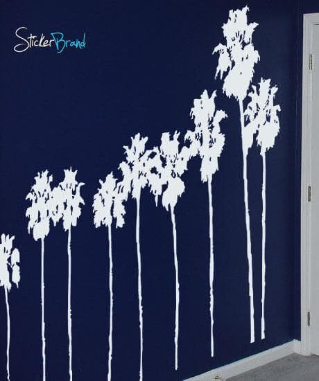 A white decal of a group of palm trees on a blue wall.