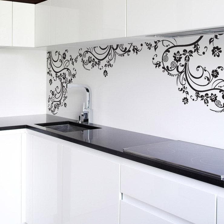 Black swirling floral decals on a white wall in a kitchen.