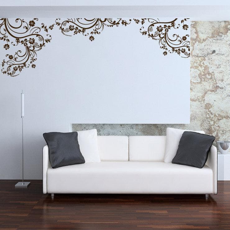 Gold swirling floral decals on a white wall above a white couch..
