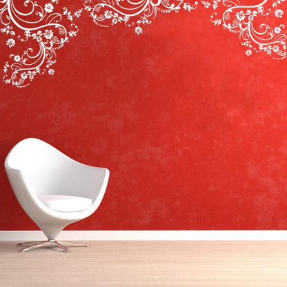 White swirling floral decals on a red wall above a white chair.