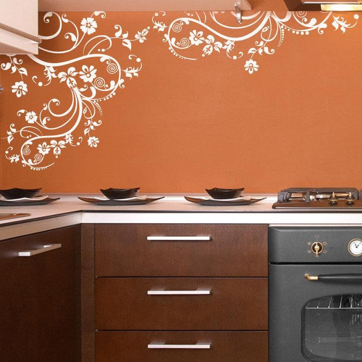 White swirling floral decals on an orange wall in a kitchen.