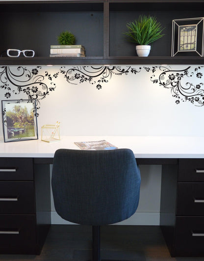 Black swirling floral decals on a white wall in a study.