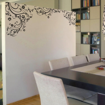 Black swirling floral decals on a white wall in a dining room.
