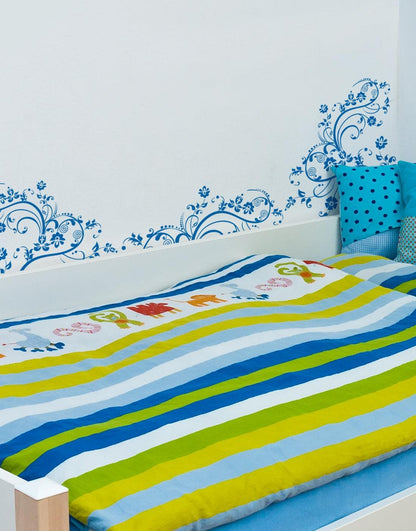 Blue swirling floral decals on a white wall in a bedroom.
