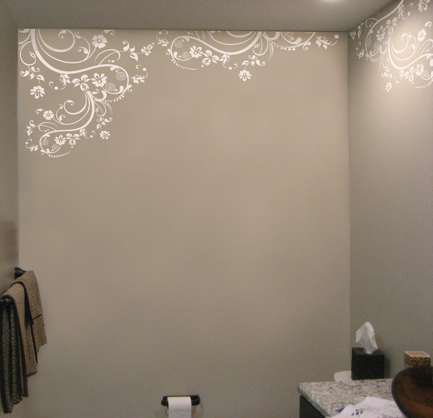 White swirling floral decals on a dark wall in a bathroom.