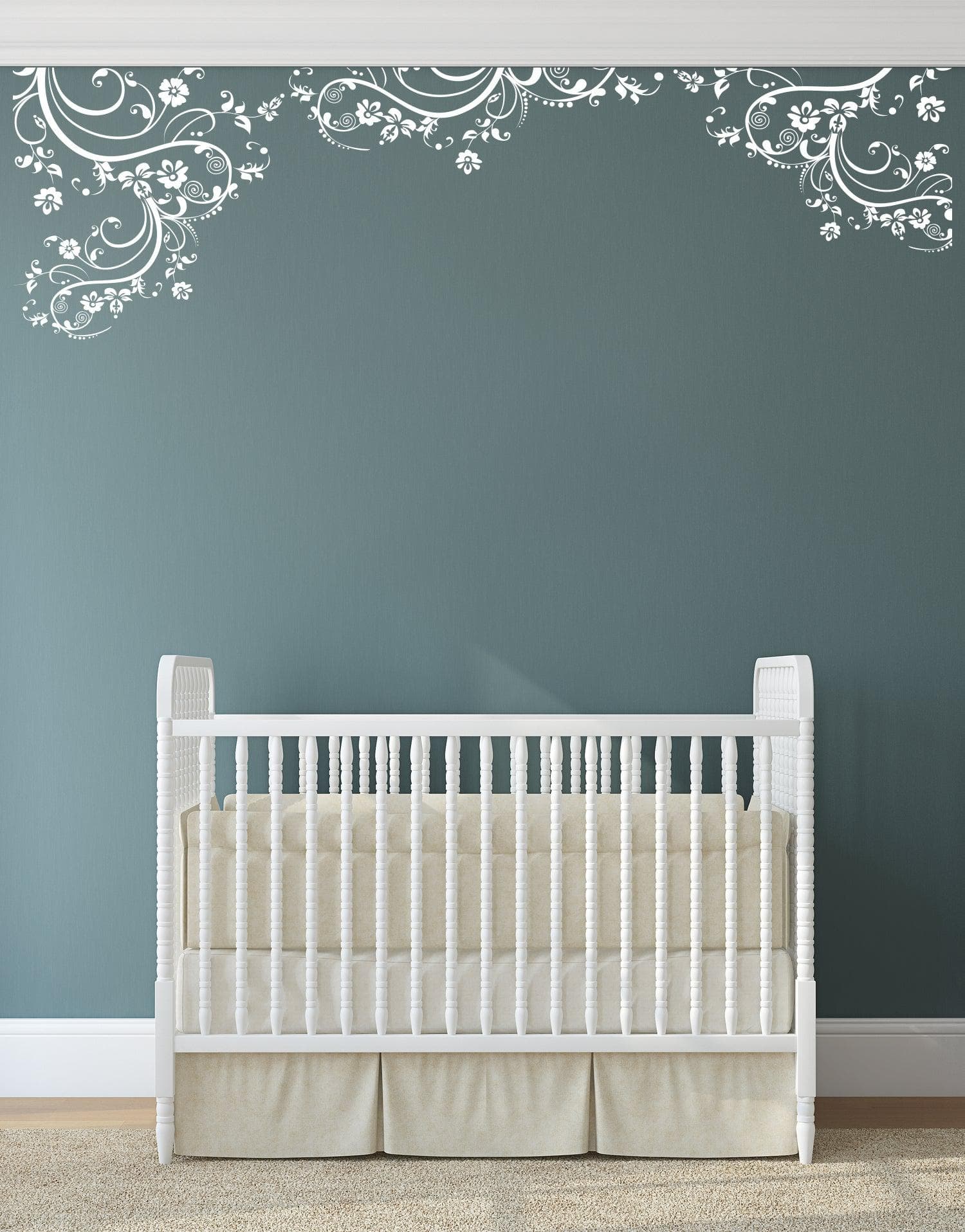 White swirling floral decals on a blue gray wall above a crib.