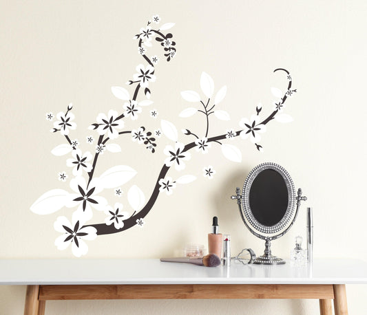 A black decal with white flowers on a white wall above a desk. 