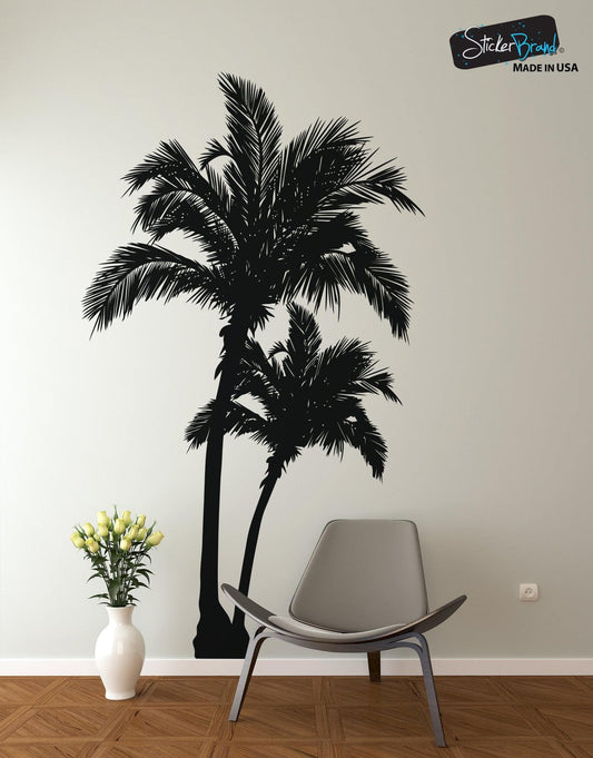 A black decal of a palm tree on a white wall near a chair and a flower vase.