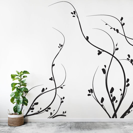 A black growing weeds decal on a white wall near a potted plant.