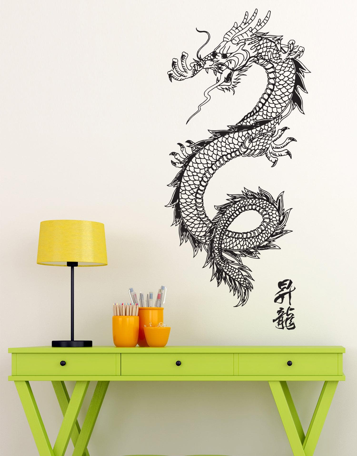 A black dragon decal on a white wall above a green table near a yellow lamp.