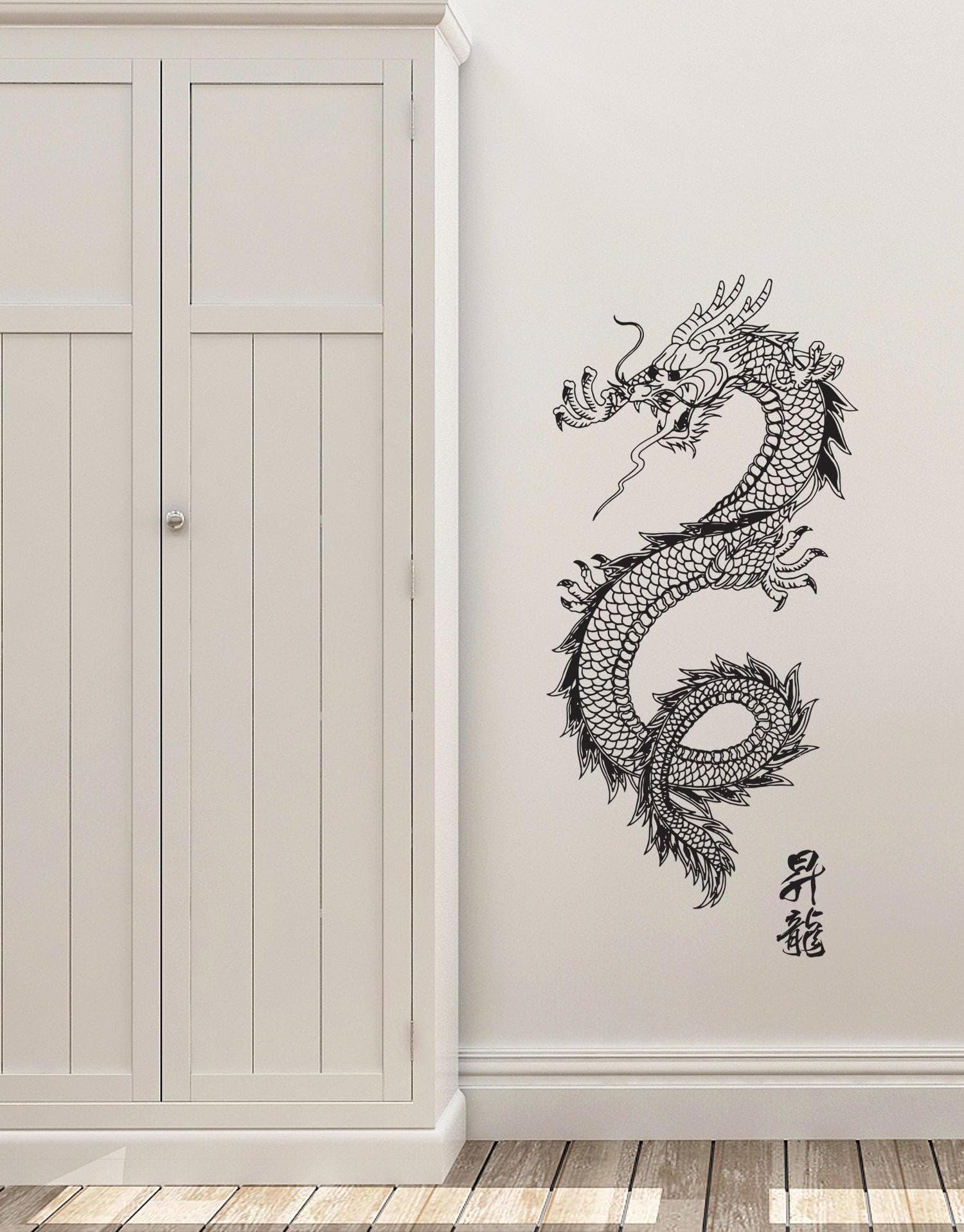 A black dragon decal on a white wall near a white cabinet.