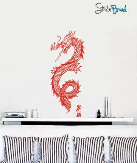 A red dragon decal on a white wall above 4 black and white striped pillows.