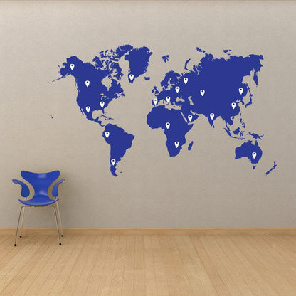 A blue world map decal with white pins on a white wall, next to a blue chair.