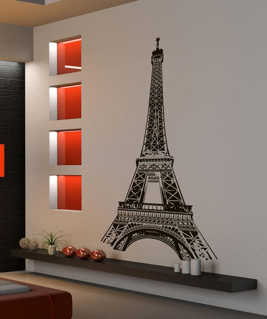 A black Eiffel Tower decal on a white wall near four square glass windows and a gray shelf. 
