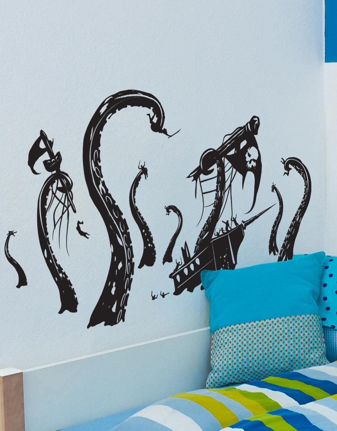 A black kraken and pirate ship decal on a white wall above a blue bed.