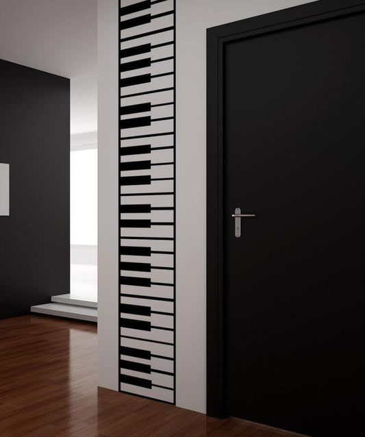 A black decal of vertical piano keys on a white wall near a black door.