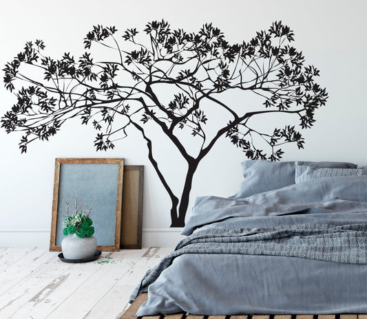Black tree decal on a white wall in a bedroom.